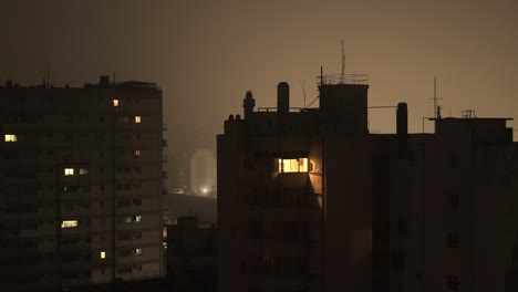 dimly lit apartment buildings in buenos aires with a lone window glowing at night