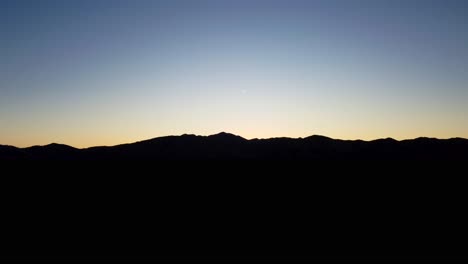 mountain silhouetted on horizon at blue hour