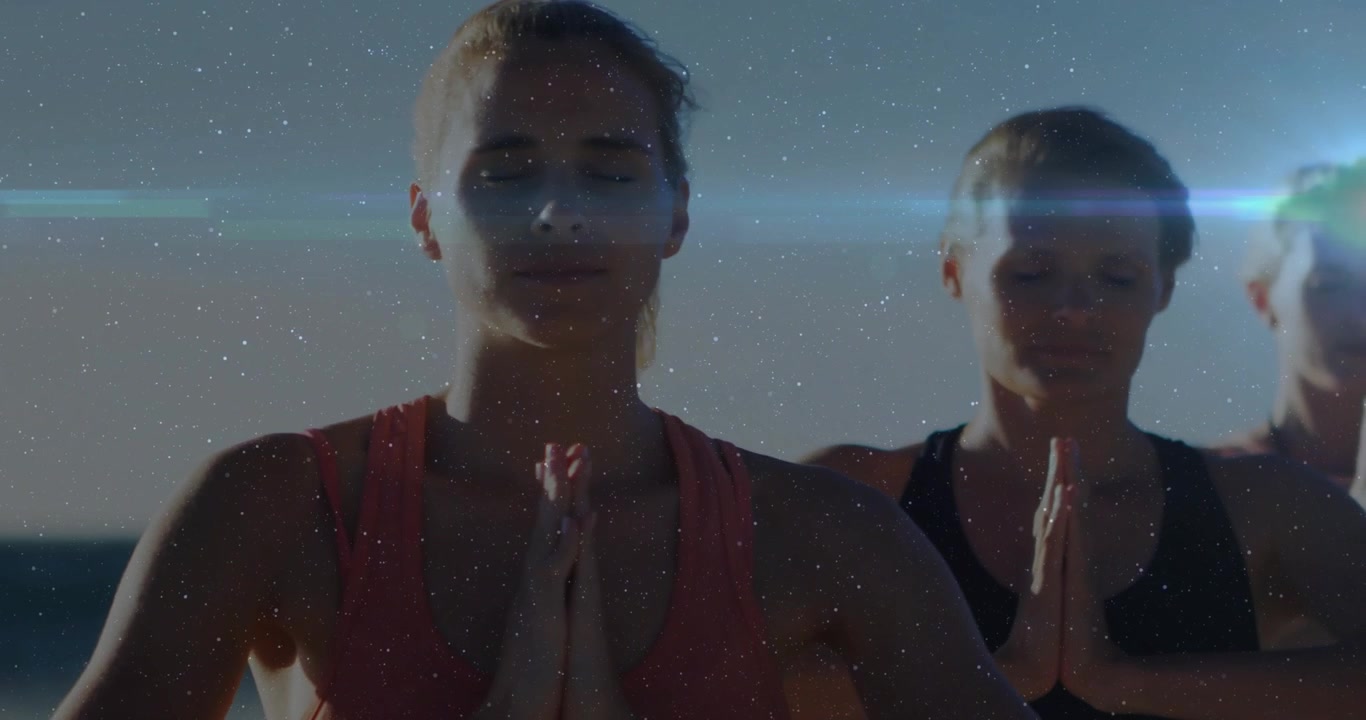 Tre donne che tengono i palmi uniti e chiudono gli occhi, praticando benessere in spiaggia con sovrapposizioni di bagliori dell'obiettivo.