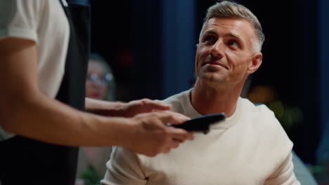 smiling businessman using credit card for payment in cafe