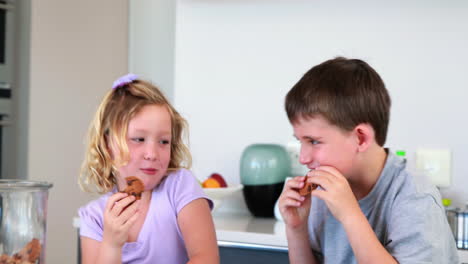 siblings taking cookies from the jar and eating them