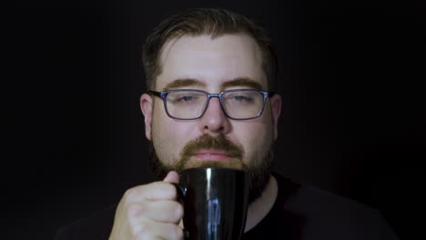 motion studio portrait of a tired, bearded man perking up after enjoying a sip of coffee