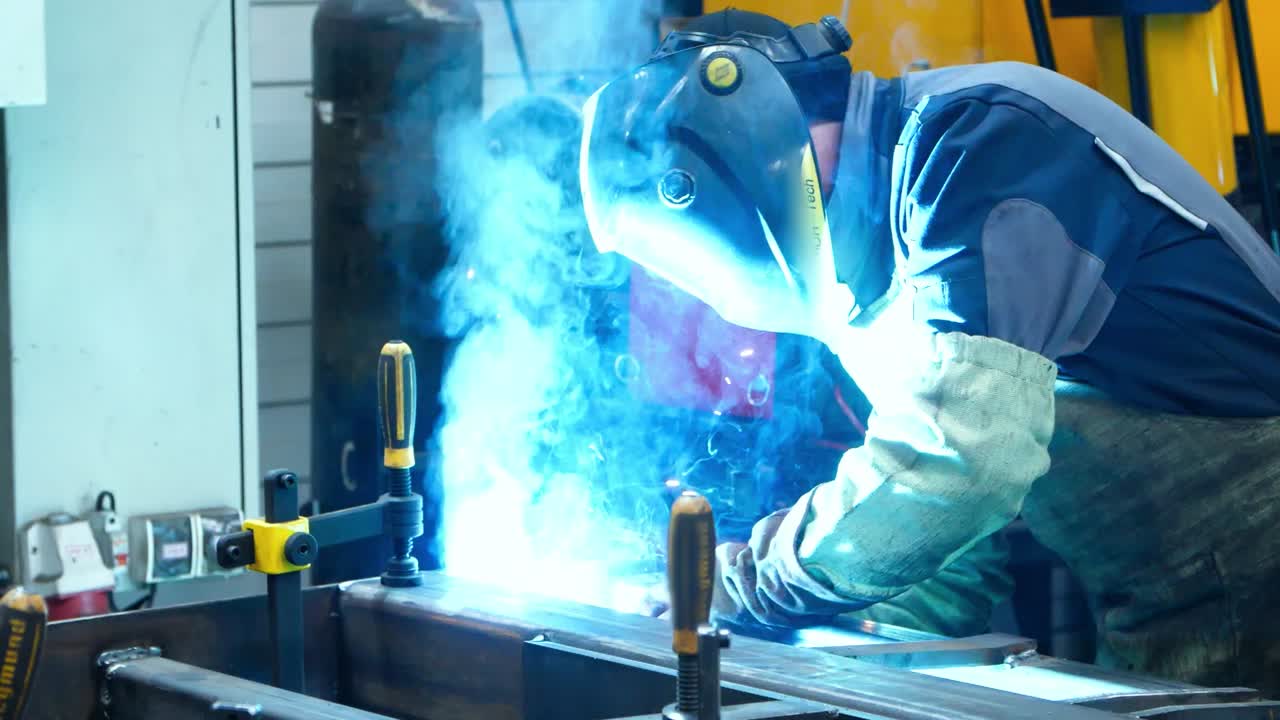 Worker making welding of metal surfaces producing many bright flashes and sparks