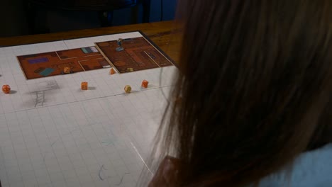 mujer tira un puñado de dados en una alfombra de juego con accesorios rpg