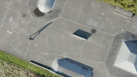 Rotating-aerial-view-of-a-skater-practicing-tricks-at-a-skatepark