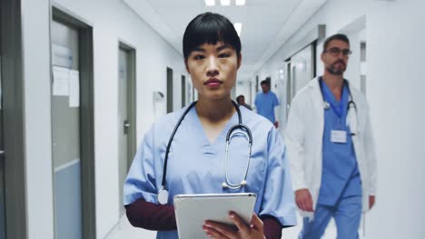 Female-doctor-standing-in-hospital-corridor-using-tablet-computer-4k