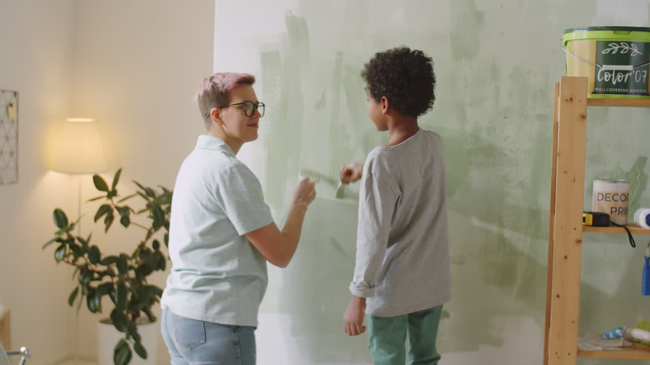 Mom and daughter painting a wall green together