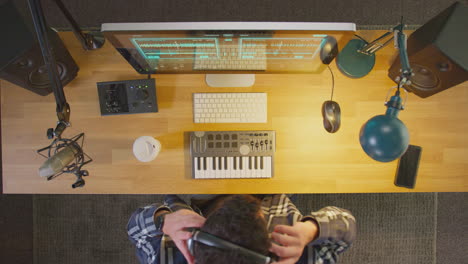 overhead view of male musician at computer in studio finishing work and turning off lights