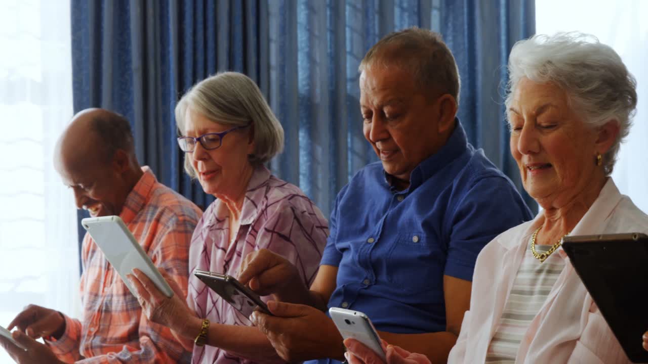 Happy senior friends using digital tablet in living room 4k