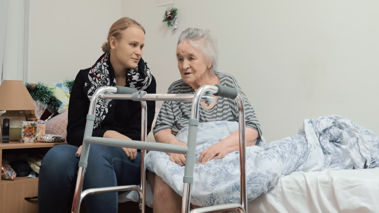 성인이 된 손녀가 병원에 있는 노인 할머니를 방문하고 있습니다.