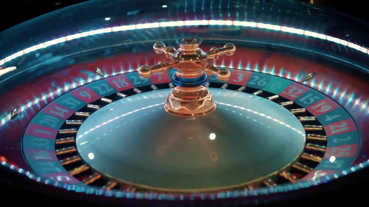 Primo piano nitido di una moderna ruota della roulette da casinò che gira velocemente. Riflessi di luce neon blu e rossa, simbolo universale di probabilità, fortuna, scommesse ad alto rischio e intrattenimento da gioco