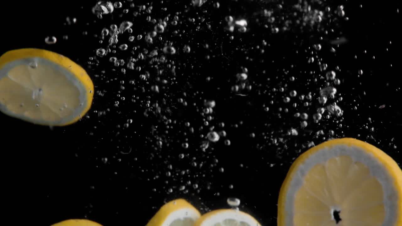 Lemon Slices Falling into Water Super Slowmotion, Black Background, lots of Air Bubbles, 4k240fps