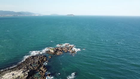 Aerial-footage-of-the-the-beautifu-rocks-and-sunny-beach-of-Armação-in-Florianópolis,-Brazil