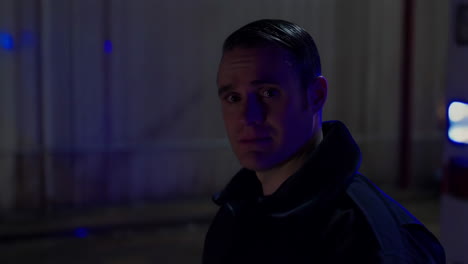 paramedic standing by an ambulance at night