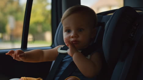 baby in a car seat looking out the window during a car ride