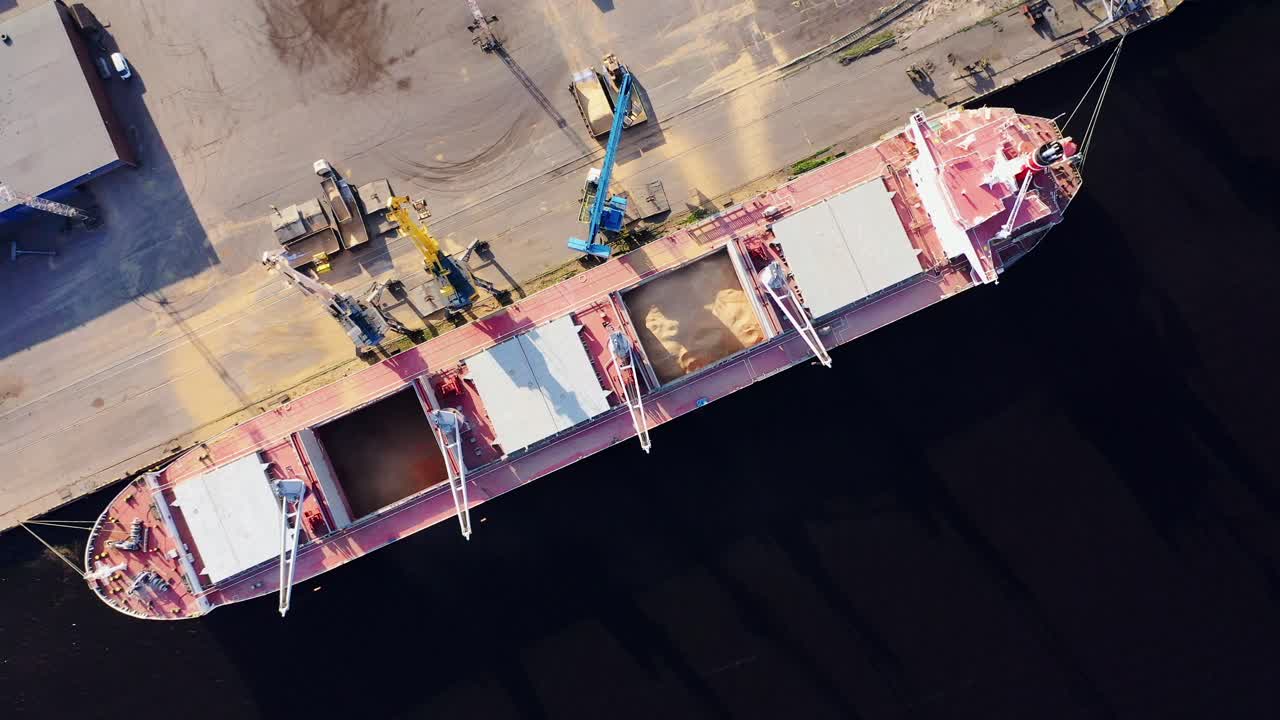 Bird's-eye view of grain terminal operations with ship docked at concrete quay