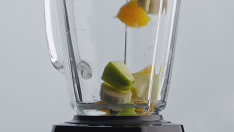 frutas frescas lanzando la licuadora en súper cámara lenta de cerca. preparando batido