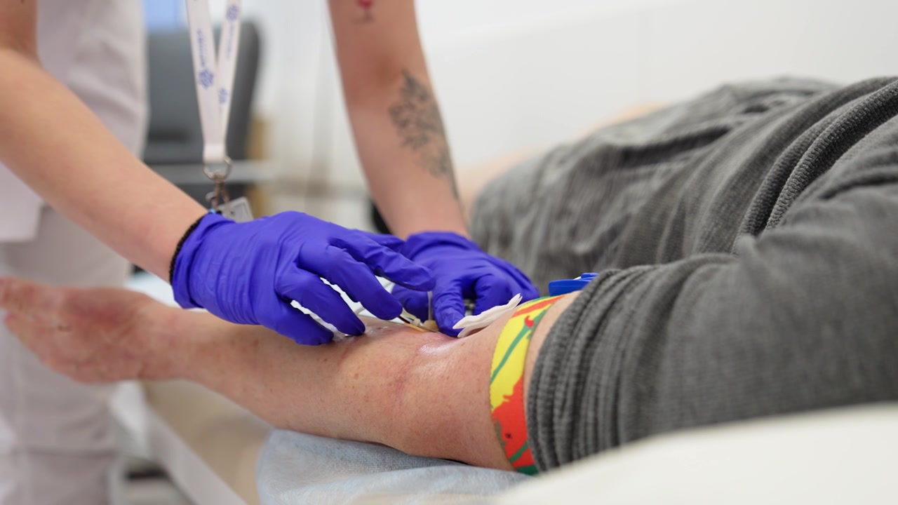 Mãos enluvadas de uma enfermeira inserem uma agulha na veia do paciente. Coletando exame de sangue de um paciente.