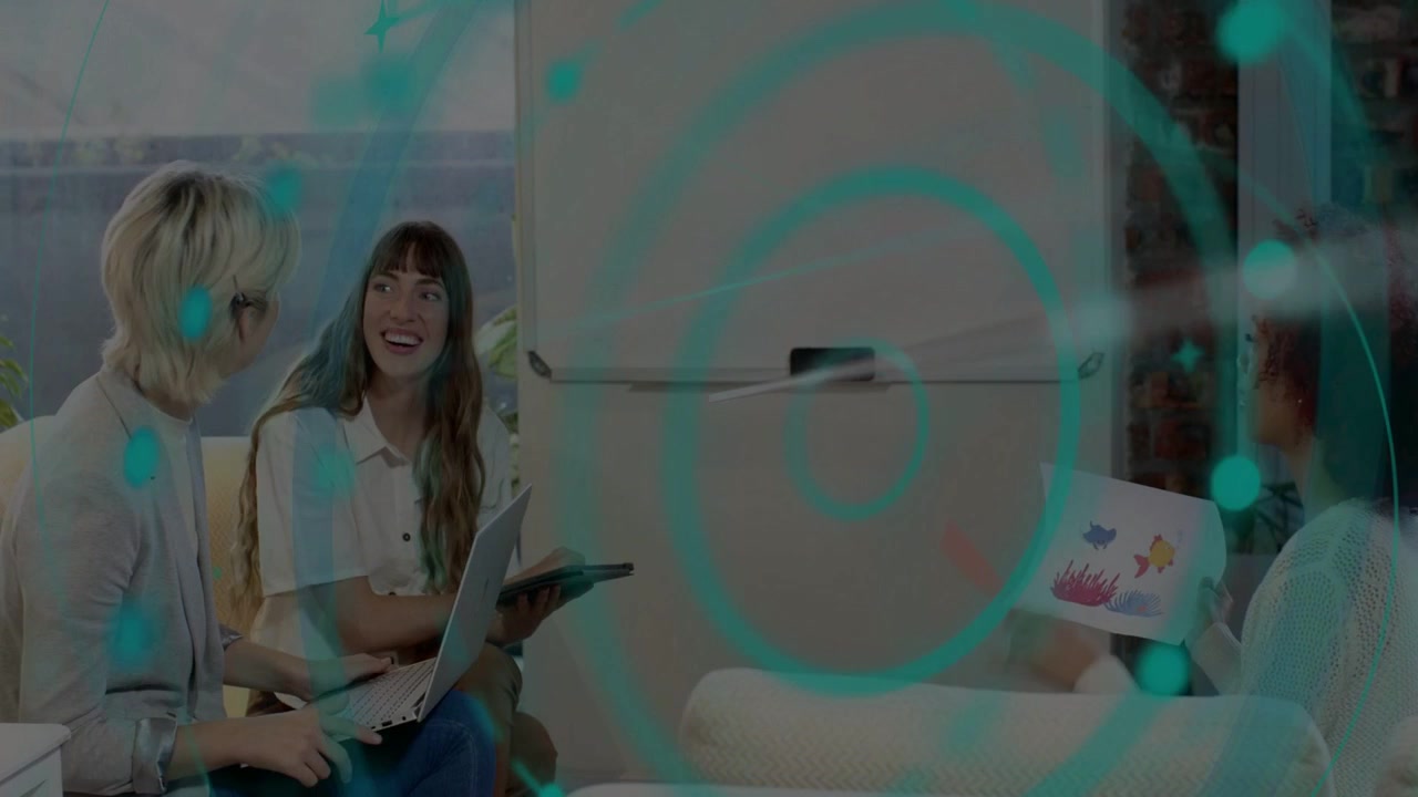 Dos mujeres inclinándose, señalando, escribiendo y respondiendo a una colega que sostiene una impresión de diseño, con una superposición verde azulado.