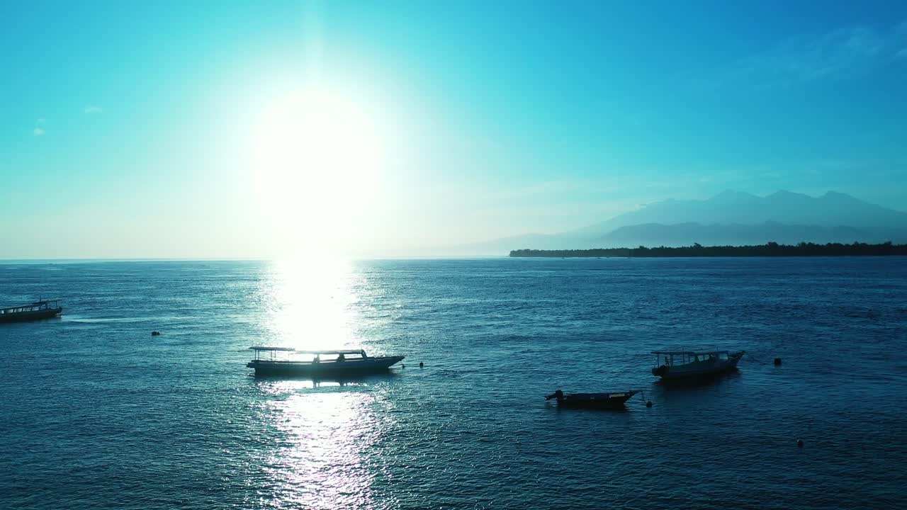 열 대 섬, 발리의 해안 근처에 떠 있는 보트와 함께 고요한 만에 햇빛을 반사 하는 맑은 하늘에서 빛나는 태양과 함께 낭만적인 일몰