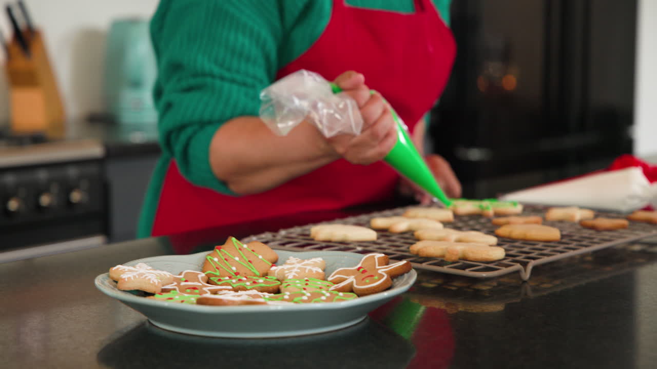 Decorating Christmas cookies with green icing in cozy kitchen setting
