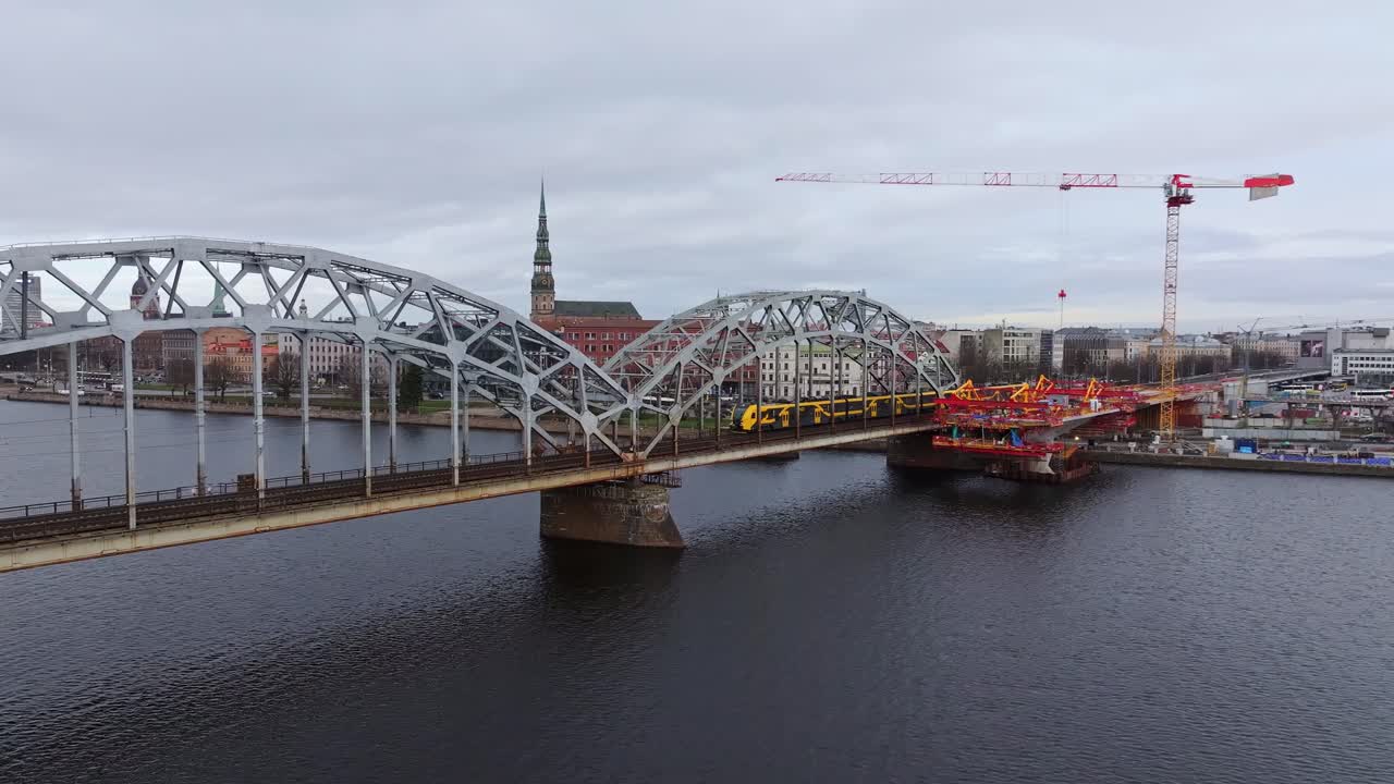 fotografía aérea de un tren que pasa por un puente ferroviario en letonia.