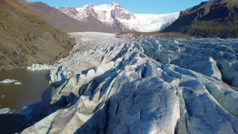 Aerial-view-of-glacier-in-Iceland,-beautiful-nature-landscape,-flying-over-blue-ice-in-mountains