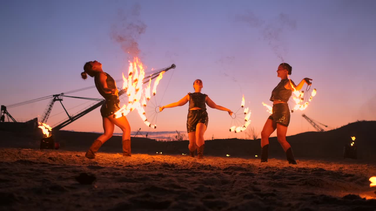 Artisti professionisti eseguono uno spettacolo di fuoco a un festival estivo sulla sabbia al rallentatore. Acrobati circensi lavorano con il fuoco di notte sulla spiaggia