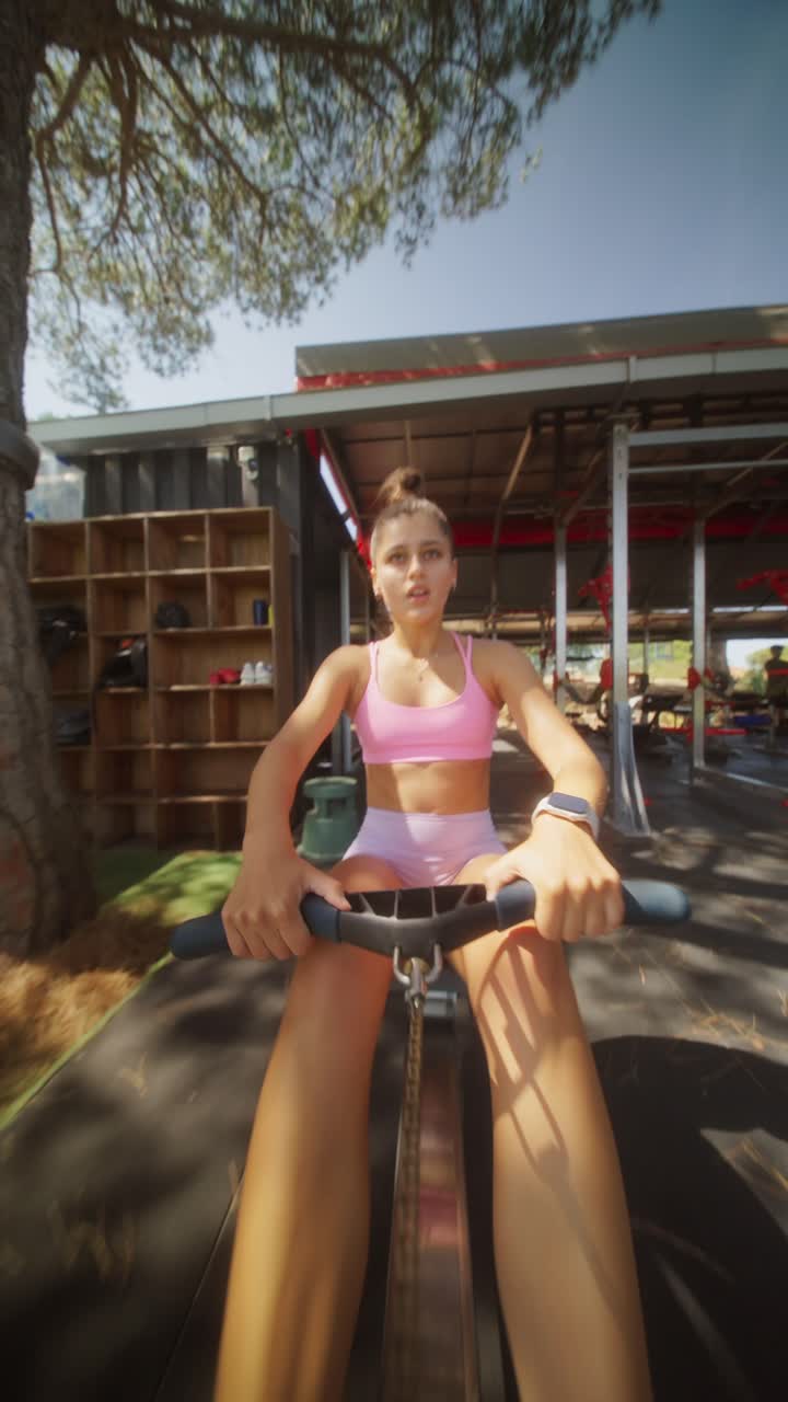 Woman Engaged in Intense Rowing Machine Workout at an Outdoor Gym