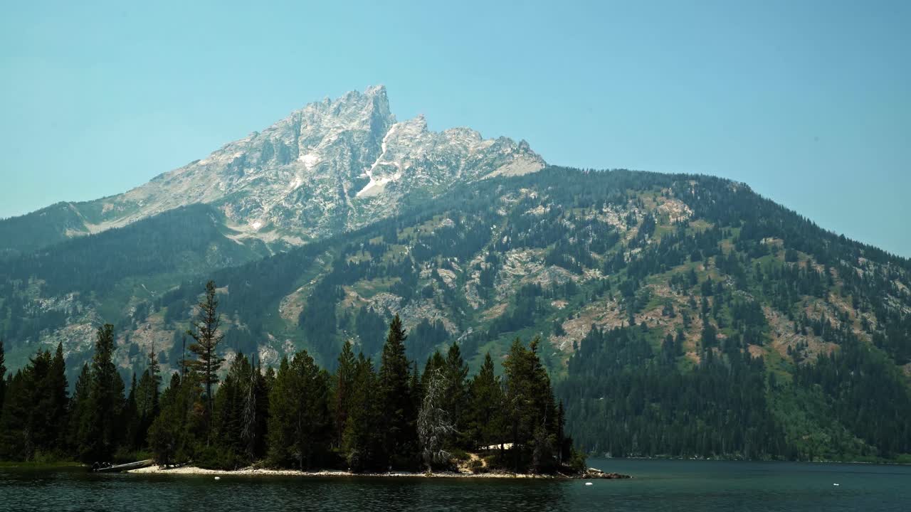 Stunning landscape nature tilting up shot of the majestic Grand Teton National Park mountain's from Jenny Lake on a warm sunny summer day near Jackson Hole, Wyoming, USA