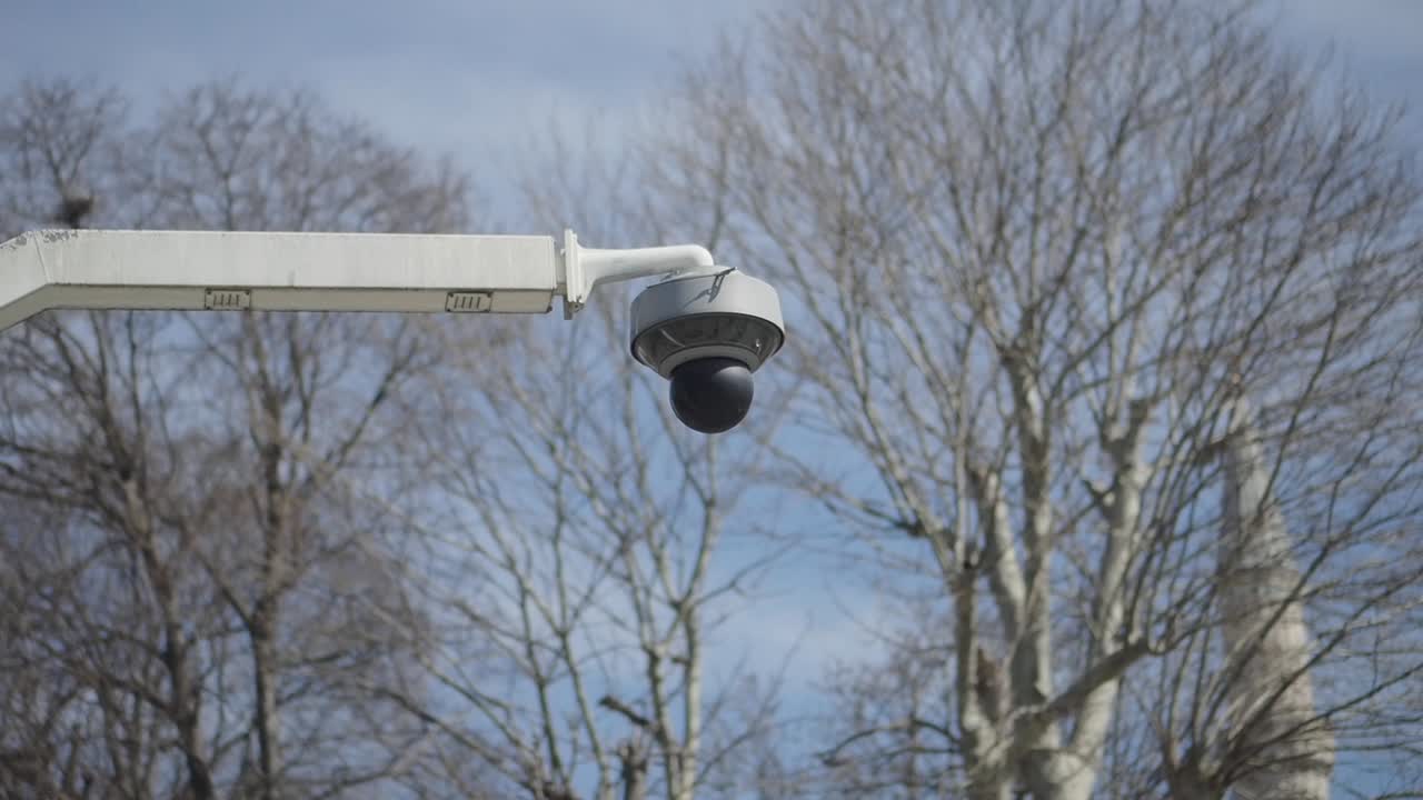 CCTV Security Camera on a Pole with Bare Trees and Minaret