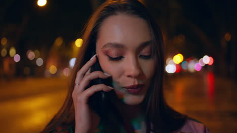 retrato de una mujer feliz llamando por teléfono celular por la noche luces de la ciudad. niña hablando por teléfono