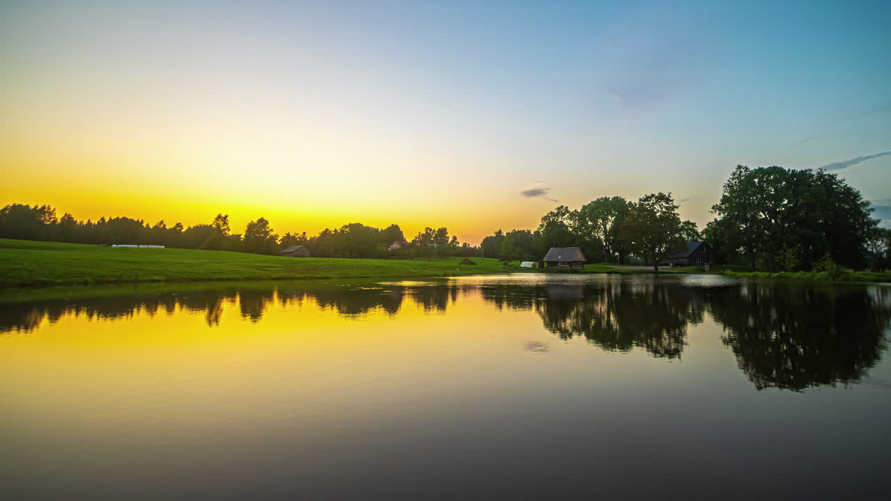 해가 지는 동안 활기찬 황금색  ⁇ 빛이 평화로운 호수 위에 반사됩니다.