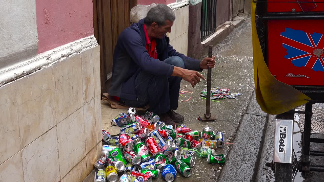 un hombre en la calle aplasta y recicla latas de aluminio en la habana cuba 1