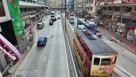 timelapse overlooking bustling urban scene of king's road in north point, hong kong, showcasing traffic and vibrant city life on a sunny day. pan up shot