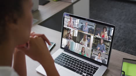 mid section of african american woman having a video conference on laptop with colleagues at office