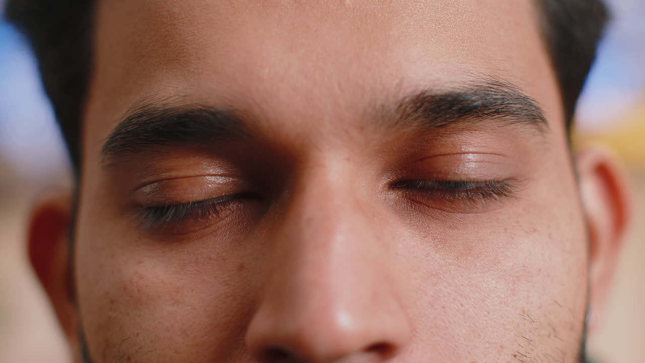 Retrato macro en primer plano de un hombre indio con la cara sonriente, ojos marrones y brillantes mirando a la cámara, parpadeando, guiñando el ojo.