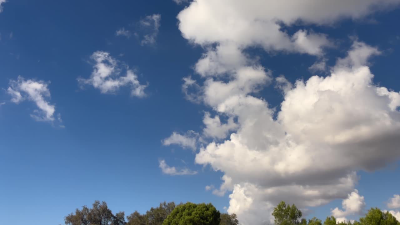 스페인 마요르카 해변 위 밝은 파란 하늘을 가로질러 뭉게뭉게 떠다니는 흰 구름