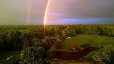 aerial drone view of a double rainbow in the countryside on a cloudy day