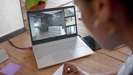 African-american-female-security-officer-watching-business-cctv-camera-views-on-laptop,-slow-motion