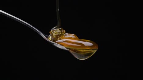 static shot from a spoon is poured over the honey against black background