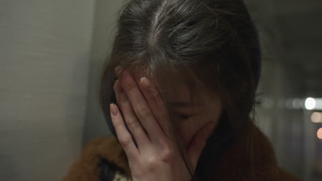 close-up shot of a tearful girl leaning against the wall of an underpass tunnel. she appears deeply unhappy, with her hand partially covering her face,a moment of intense emotional vulnerability