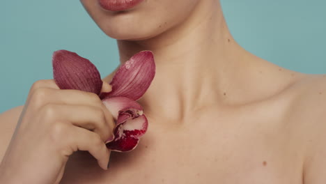 close up beauty portrait woman touching body with red orchid flower caressing smooth healthy skin complexion enjoying fresh natural fragrance skincare concept