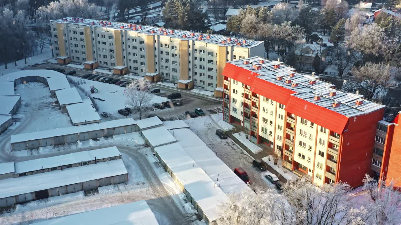 Asuinrakennuksia, autotalleja ja puita kuuran peitossa talvisessa lumessa aurinkoisena aamuna, ilmakuva.