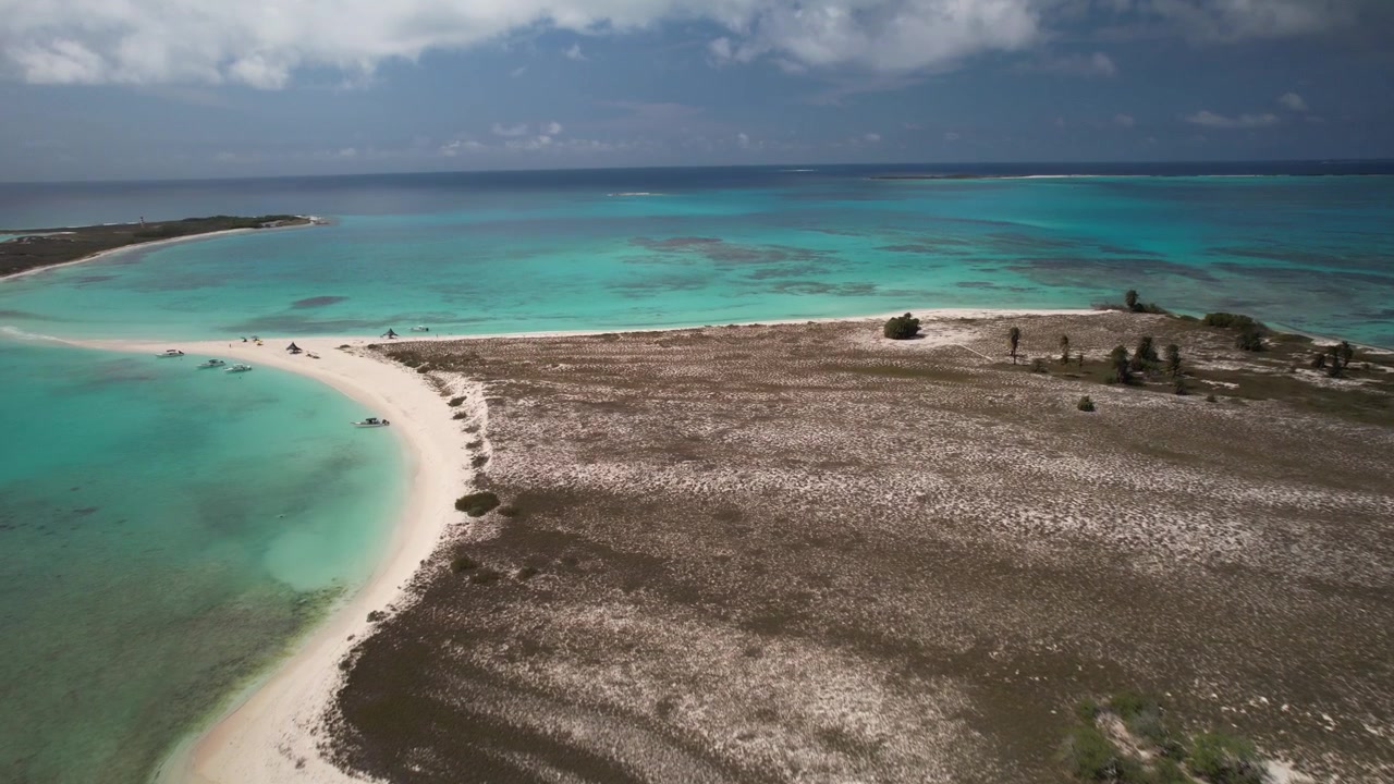 Kumlu plajı, bitki örtüsü ve turkuaz deniziyle Cayo de Agua'ya havadan yaklaşım, drone yükselip aşağı eğiliyor