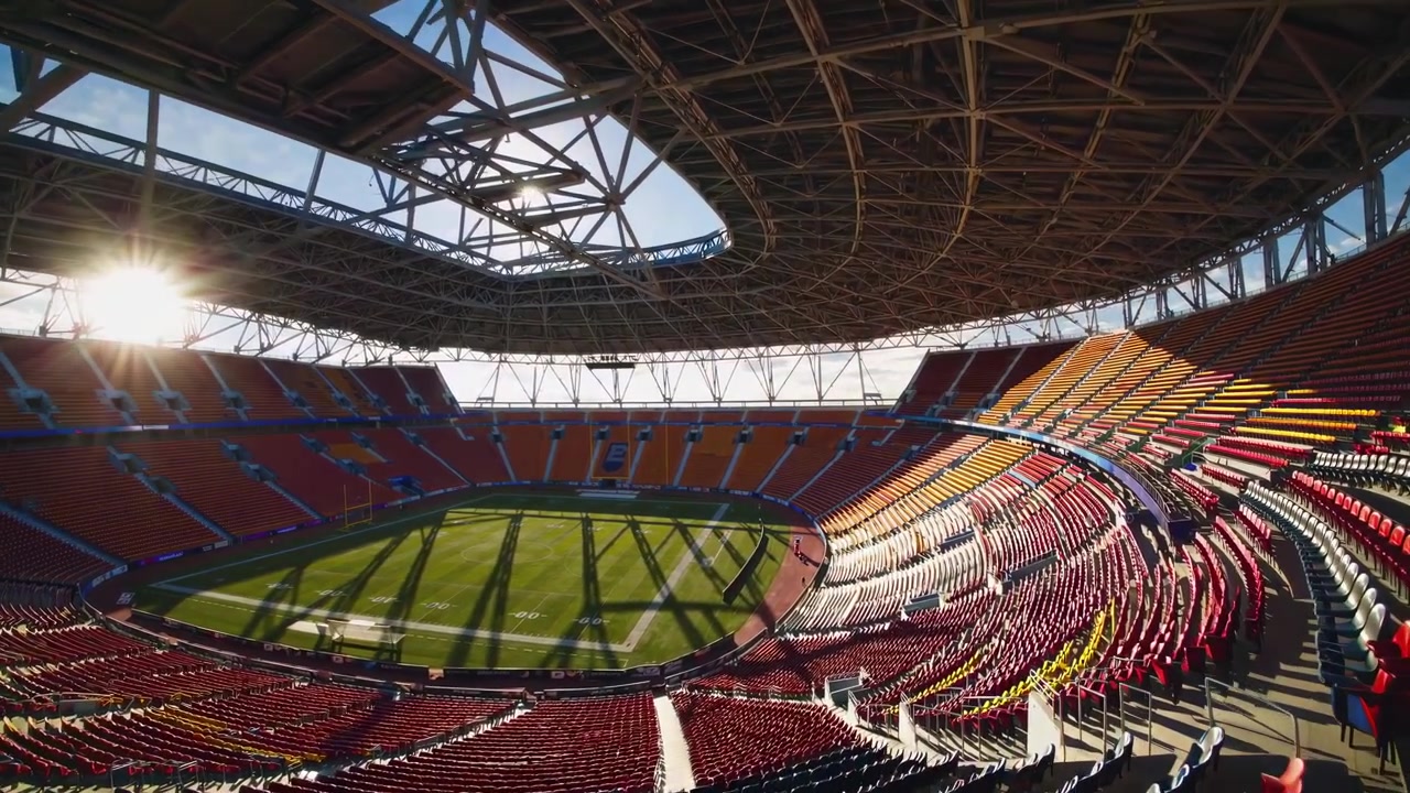 Stadio di calcio moderno vuoto con la luce del sole che filtra dal tetto