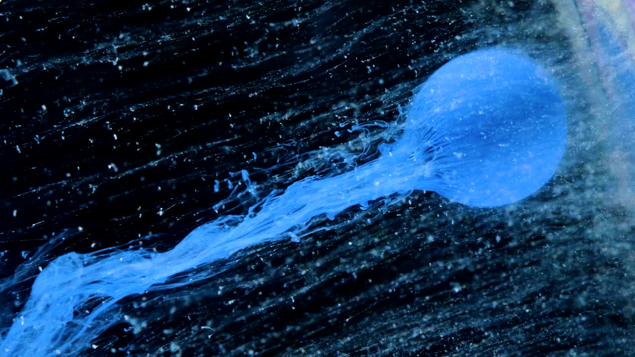 다채로운 잉크 페인트가 천천히 공에서 흘러나옵니다.