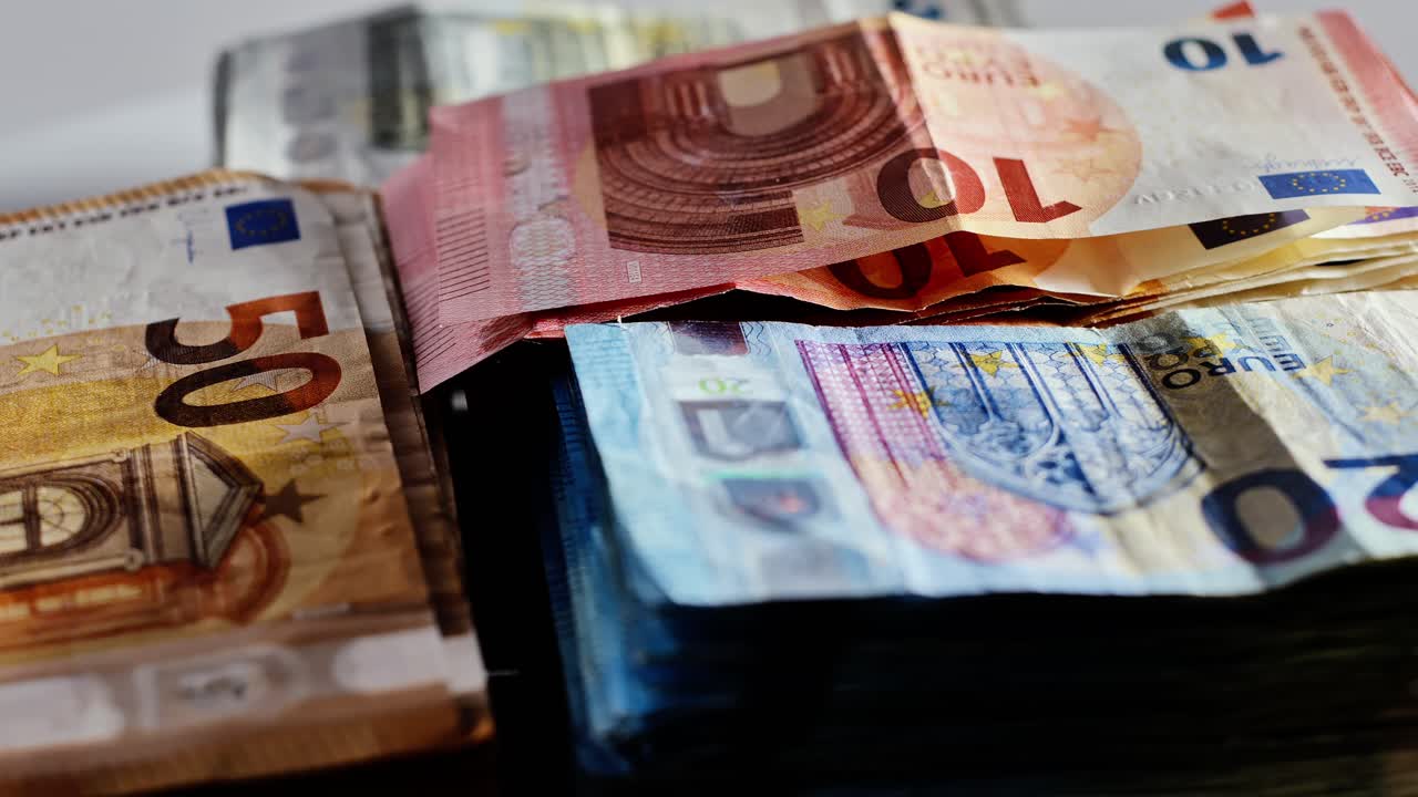 Slow motion view of colorful euro bills turning on table, economic concept frame