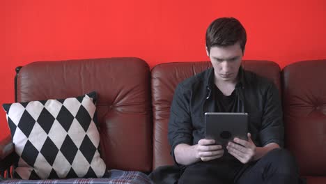 young man looking at a tablet on a couch