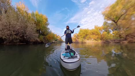 paddle boarder remando por el río salado inferior en un hiperlapso borroso de movimiento.